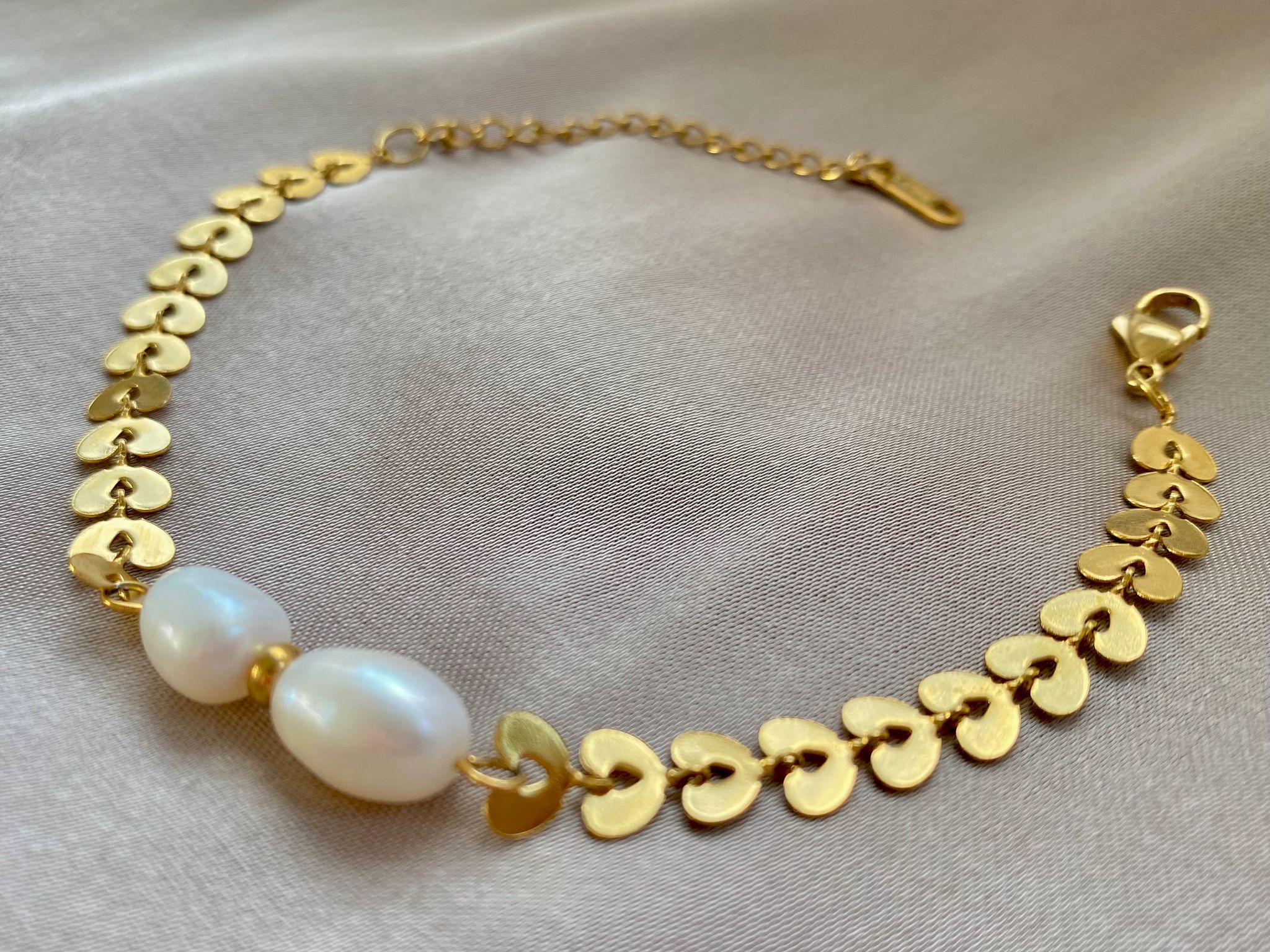 Nahaufnahme der mattierten Herz-Elemente und der natürlichen Oberflächenstruktur der Süßwasserperlen des Ivy Pearl Armbands.