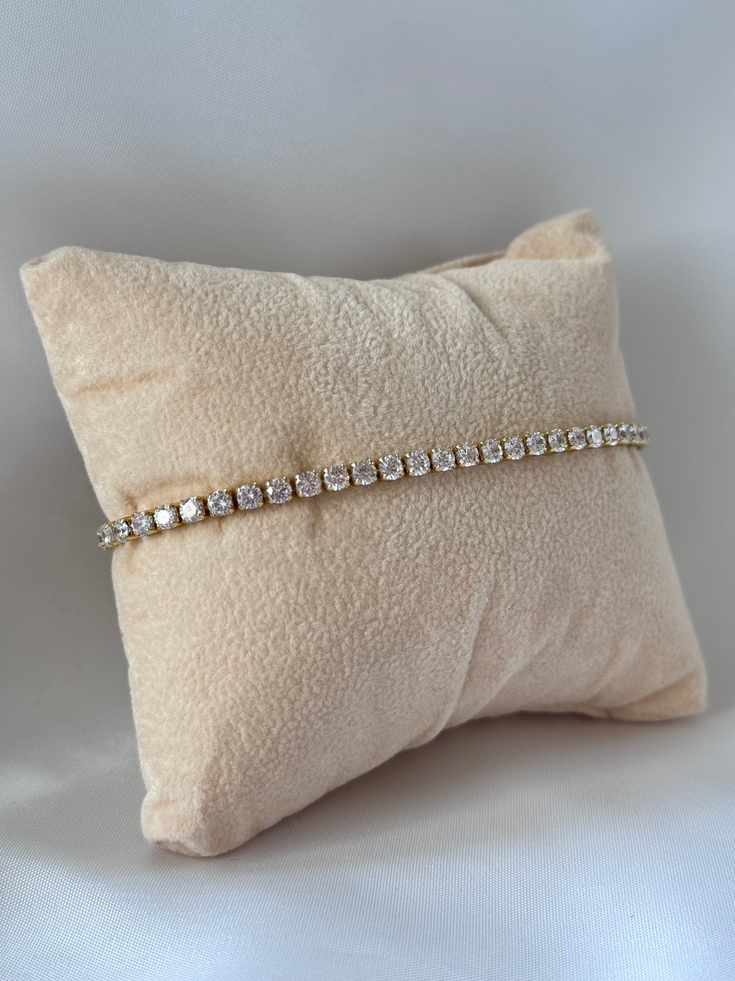 Tennisarmband aus kupfervergoldetem Metall mit funkelnden Zirkonia-Steinen, verstellbarem Schiebeverschluss und elegantem, glänzendem Design.