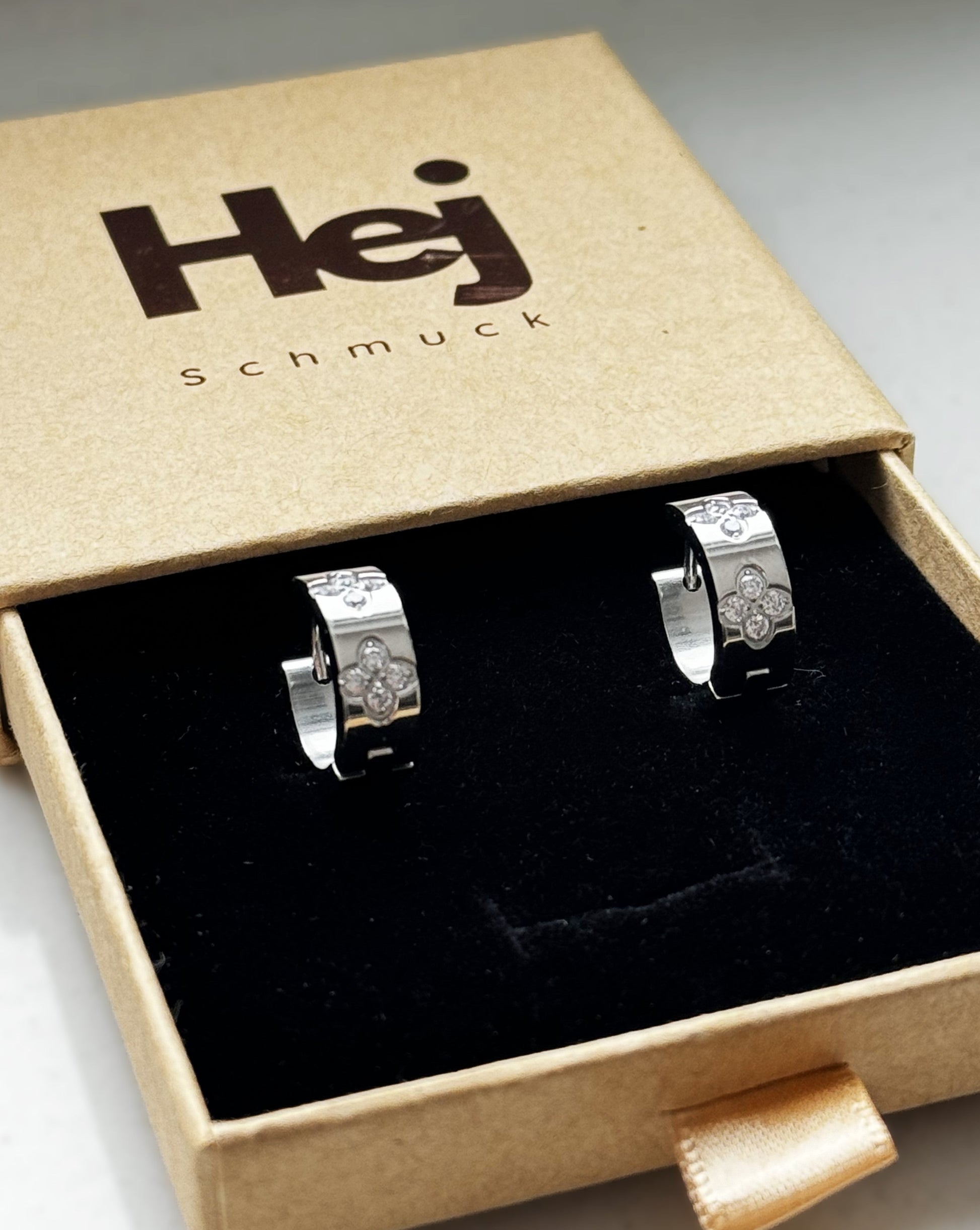 Die funkelnden silbernen Mel-Ohrringe strahlen zeitlose Eleganz aus. Hergestellt aus Edelstahl und vergoldet mit 18 Karat Gold, sind sie mit glitzernden Zirkoniasteinen besetzt. Ihr vielseitiges Design macht sie zu einem perfekten Accessoire für jeden Anlass.