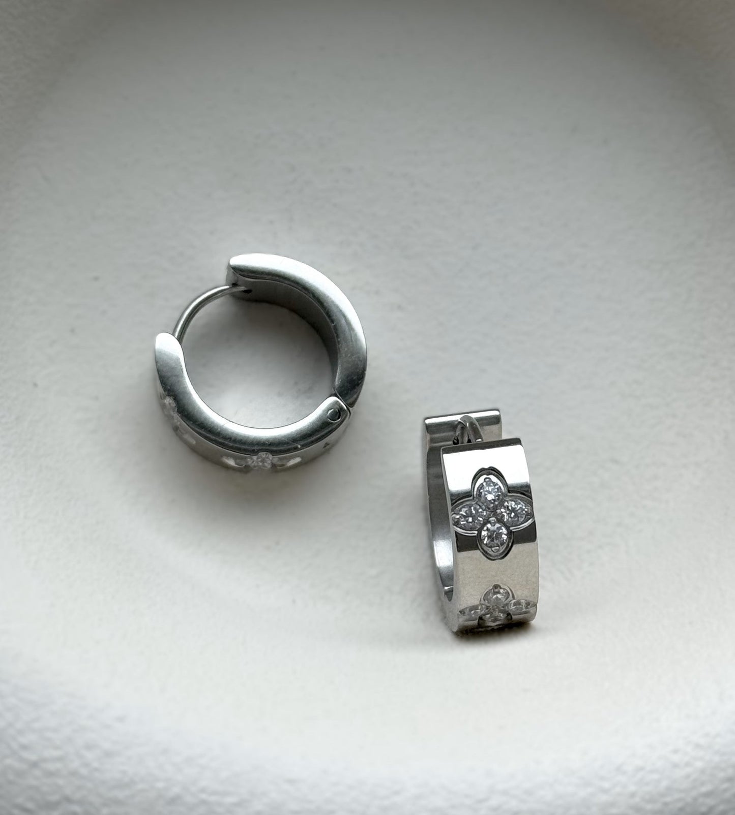 Die funkelnden silbernen Mel-Ohrringe strahlen zeitlose Eleganz aus. Hergestellt aus Edelstahl und vergoldet mit 18 Karat Gold, sind sie mit glitzernden Zirkoniasteinen besetzt. Ihr vielseitiges Design macht sie zu einem perfekten Accessoire für jeden Anlass.