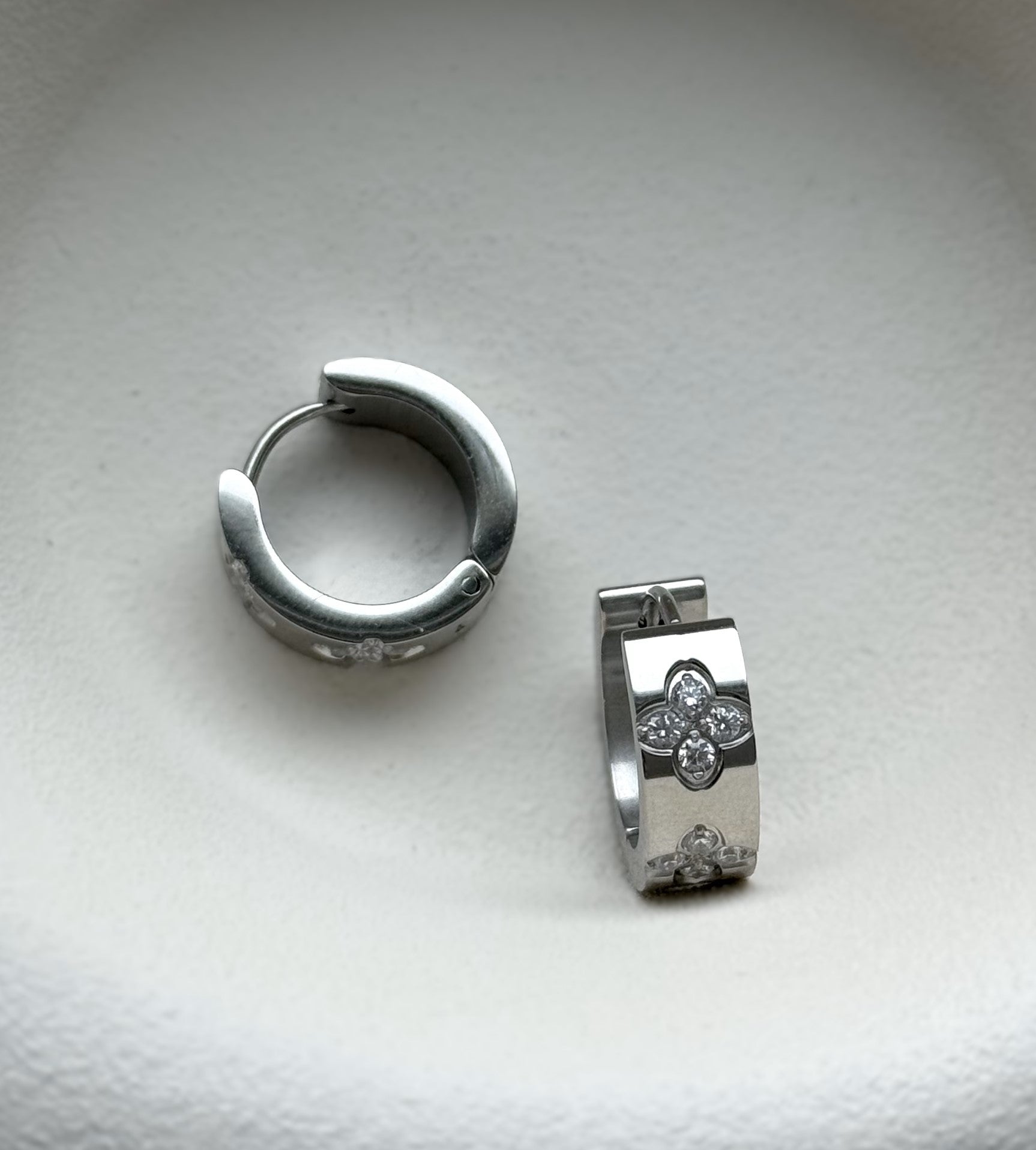 Die funkelnden silbernen Mel-Ohrringe strahlen zeitlose Eleganz aus. Hergestellt aus Edelstahl und vergoldet mit 18 Karat Gold, sind sie mit glitzernden Zirkoniasteinen besetzt. Ihr vielseitiges Design macht sie zu einem perfekten Accessoire für jeden Anlass.