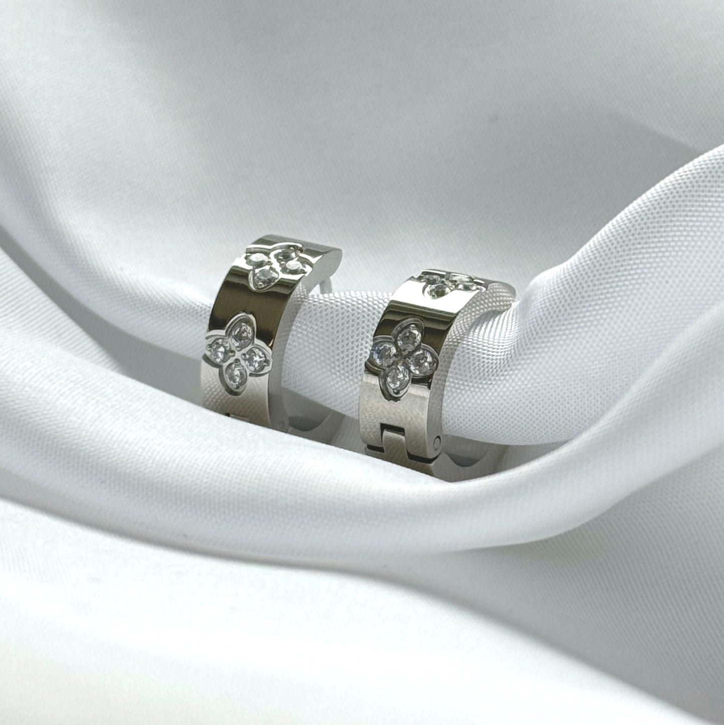 Die funkelnden silbernen Mel-Ohrringe strahlen zeitlose Eleganz aus. Hergestellt aus Edelstahl und vergoldet mit 18 Karat Gold, sind sie mit glitzernden Zirkoniasteinen besetzt. Ihr vielseitiges Design macht sie zu einem perfekten Accessoire für jeden Anlass.