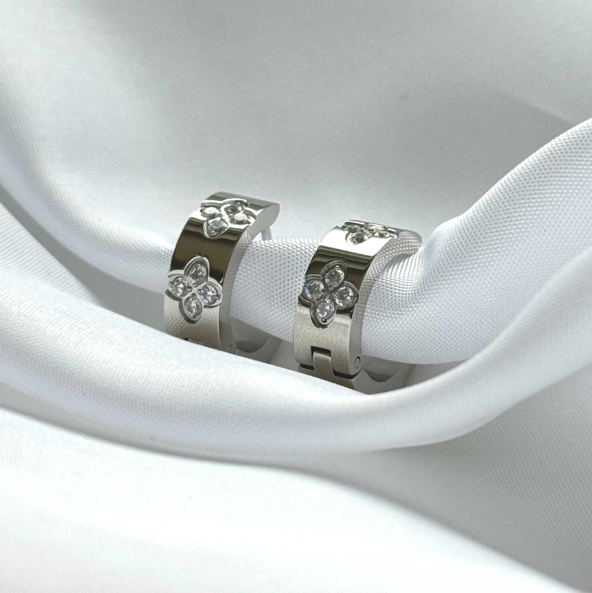 Die funkelnden silbernen Mel-Ohrringe strahlen zeitlose Eleganz aus. Hergestellt aus Edelstahl und vergoldet mit 18 Karat Gold, sind sie mit glitzernden Zirkoniasteinen besetzt. Ihr vielseitiges Design macht sie zu einem perfekten Accessoire für jeden Anlass.