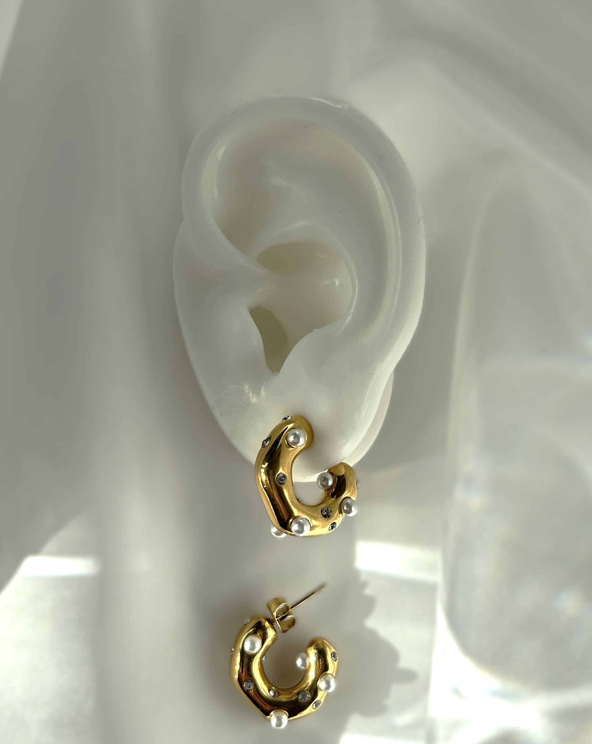 Entdecke raffinierte Eleganz mit unseren exquisiten Cody Edelstahl-Creolen. Verziert mit funkelnden Zirkonia-Steinen und zarten Perlen, vereinen diese Schmuckstücke zeitloses Design mit moderner Eleganz. Ein wahres Statement für deinen individuellen Stil.