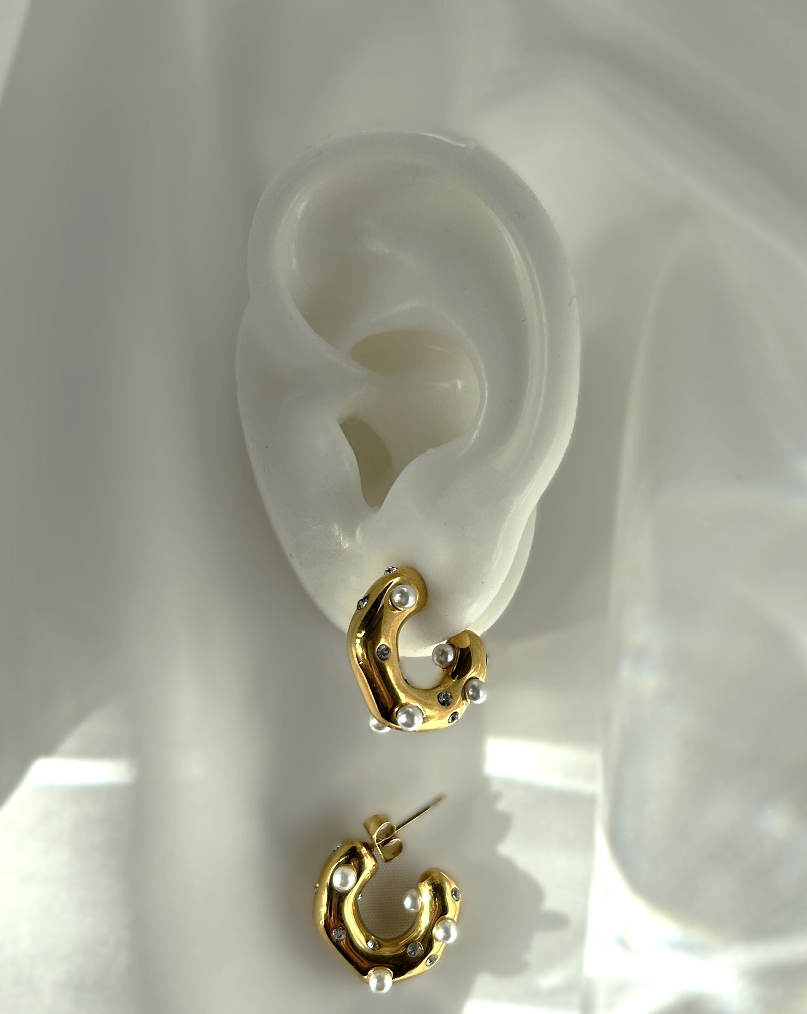 Entdecke raffinierte Eleganz mit unseren exquisiten Cody Edelstahl-Creolen. Verziert mit funkelnden Zirkonia-Steinen und zarten Perlen, vereinen diese Schmuckstücke zeitloses Design mit moderner Eleganz. Ein wahres Statement für deinen individuellen Stil.