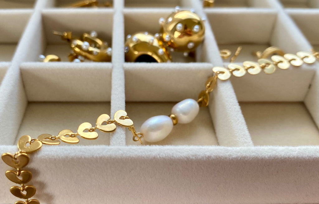 Nahaufnahme der mattierten Herz-Elemente und der natürlichen Oberflächenstruktur der Süßwasserperlen des Ivy Pearl Armbands.