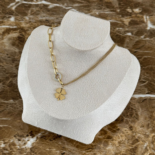 Nahaufnahme des Amara Anhängers: Ein funkelnder, mit Zirkonia-Steinen besetzter Ring hält ein goldenes Kleeblatt an der 14k vergoldeten Edelstahlkette.