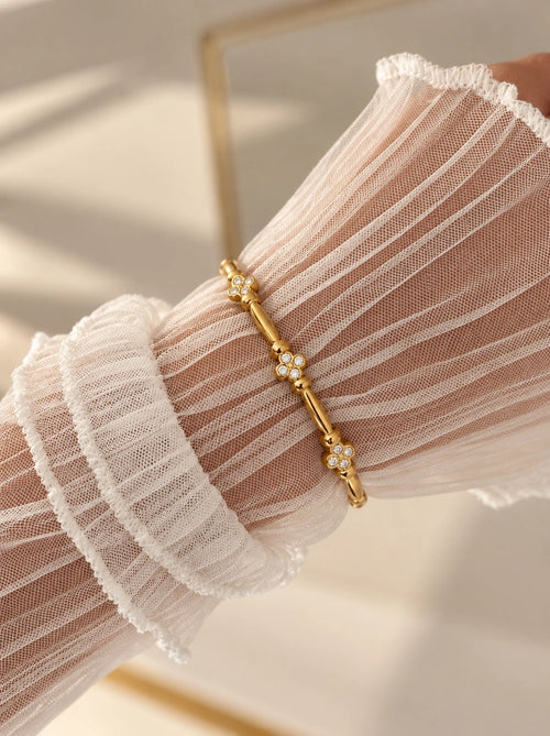 Tragebild des Amber Armreifs aus 14k vergoldetem Edelstahl mit Kleeblatt-Zirkonia-Elementen am Handgelenk.