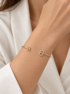 Frau trägt den Athena Armreif in Gold mit Pavé-Zirkonia zur weißen Bluse