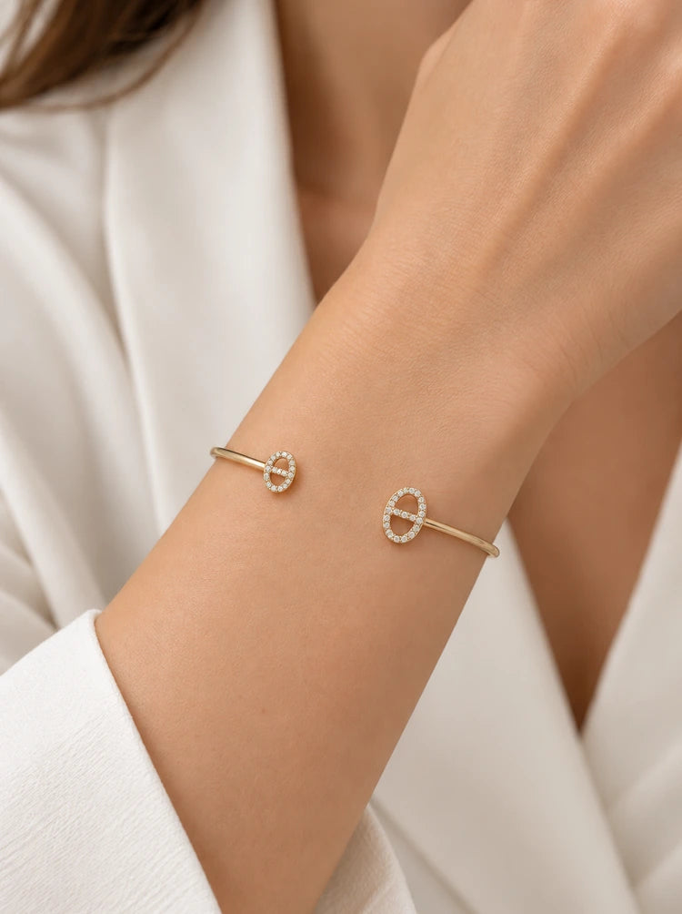 Frau trägt den Athena Armreif in Gold mit Pavé-Zirkonia zur weißen Bluse