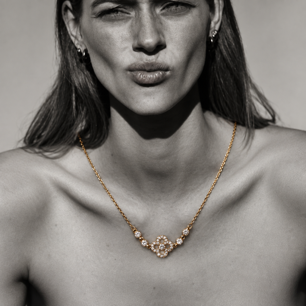Nahaufnahme der vergoldeten Clara Kleeblatt-Kette im modernen High-Fashion Editorial-Look.