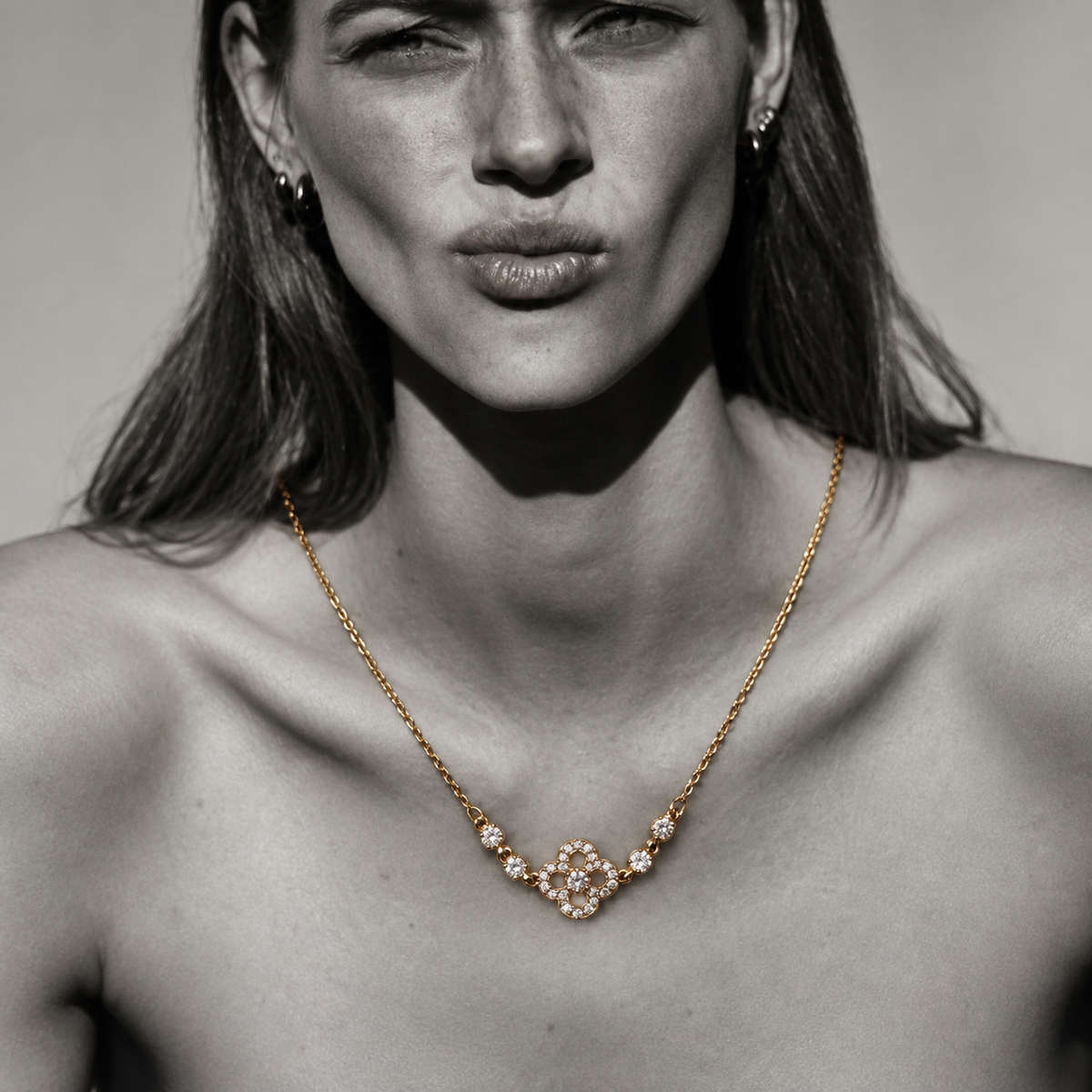 Nahaufnahme der vergoldeten Clara Kleeblatt-Kette im modernen High-Fashion Editorial-Look.