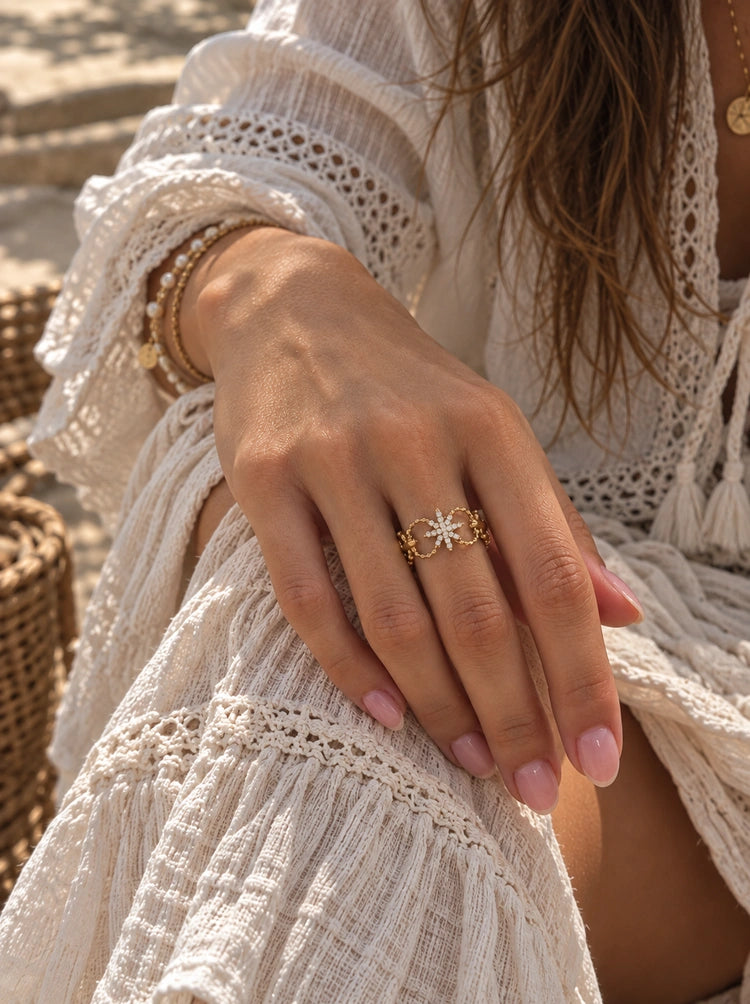 Crystal Nova Ring mit funkelndem Sternenmotiv getragen am Finger zu einem weißen Boho-Outfit.