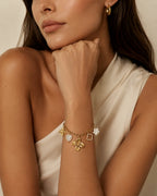 Tragebild des Elicia Charm-Armbands aus 14k vergoldetem Edelstahl mit Blüten- und Herzanhängern am Handgelenk.