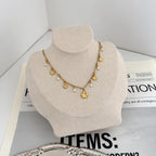 Fiora Halskette in Gold mit Blüten-Charms auf heller Schmuckbüste