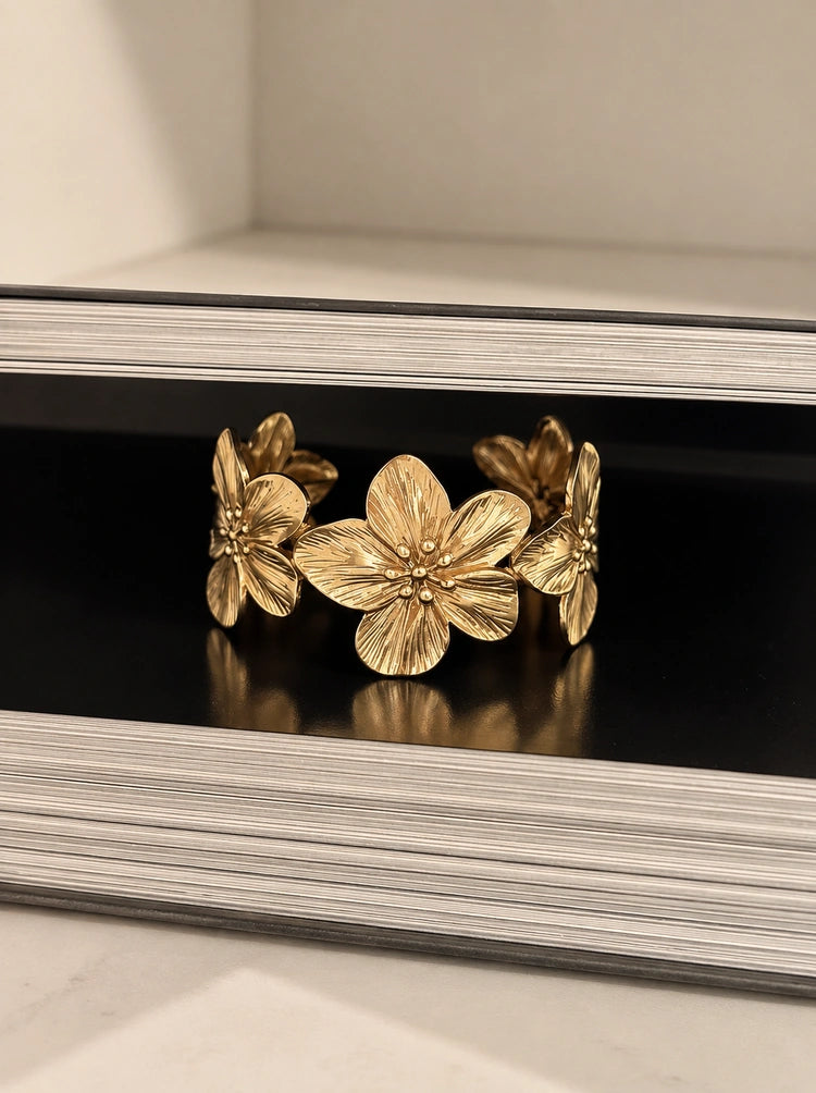 Nahaufnahme des verstellbaren Florencia Bangle Armreifs mit feingestanzten Blütenblättern dekoriert auf einem Buch.