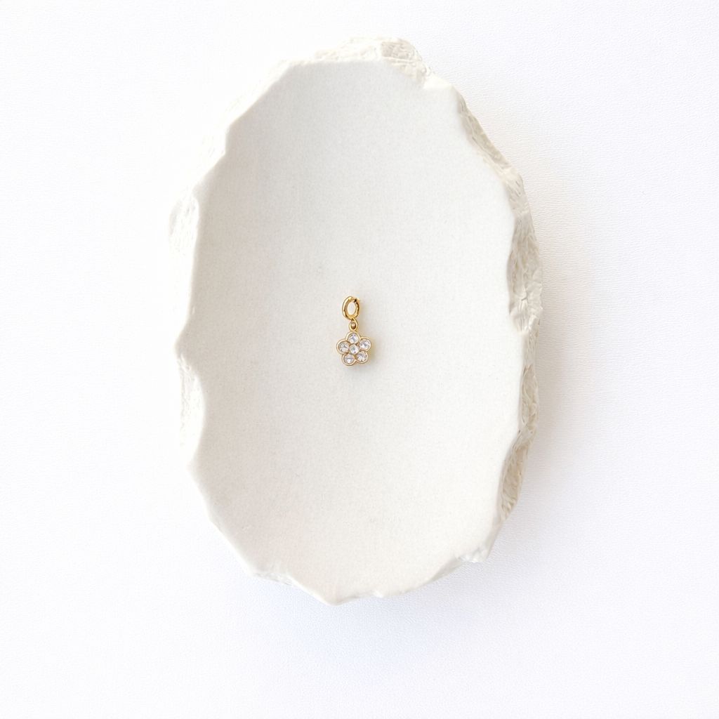 Goldfarbener Blumen-Anhänger aus 14k vergoldetem Edelstahl mit sechs großen Zirkonia-Steinen und einem runden Spring-Clasp-Verschluss auf weißem Hintergrund.