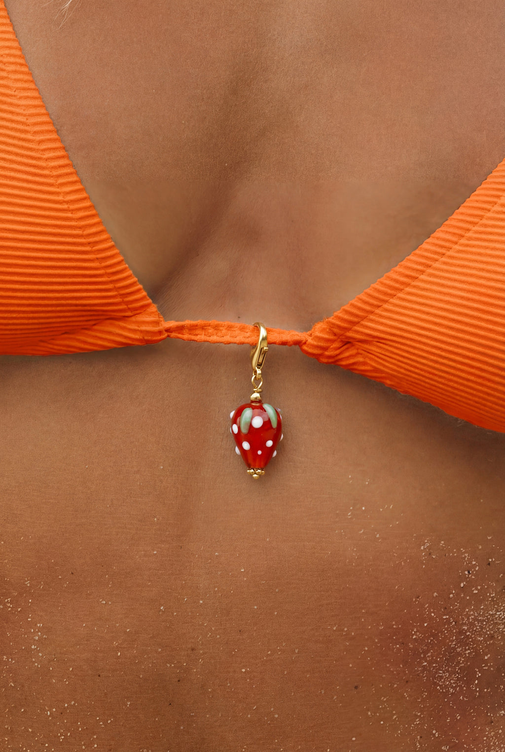 Hejschmuck Fragolita Erdbeere aus Resin und Edelstahl als wasserfester Anhänger an einem orangenen Bikini.