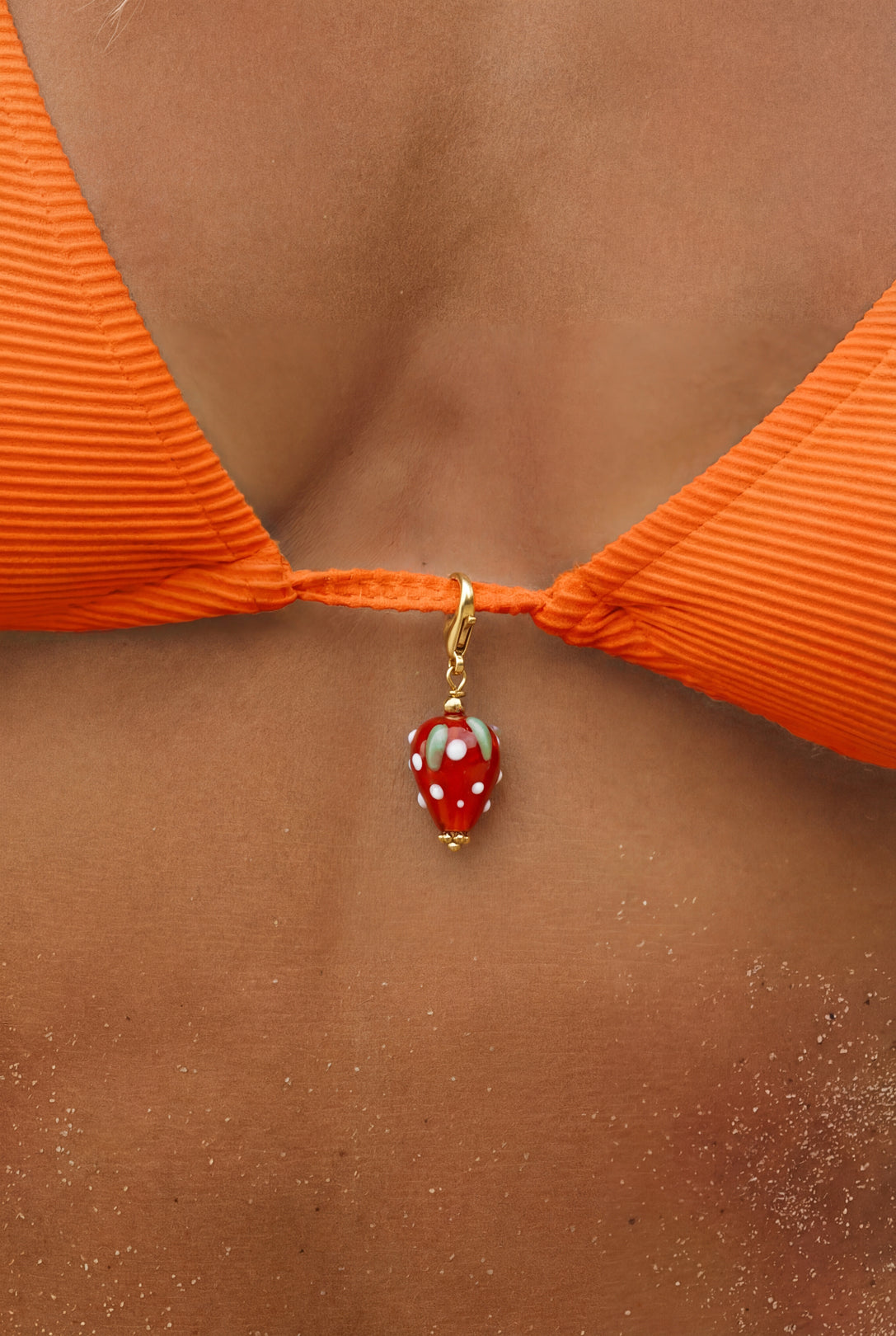 Hejschmuck Fragolita Erdbeere aus Resin und Edelstahl als wasserfester Anhänger an einem orangenen Bikini.