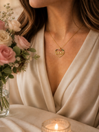 Moderne Frau trägt die goldene MOM Herz-Halskette von Hejschmuck als emotionales Statement-Piece zum eleganten weißen Outfit.