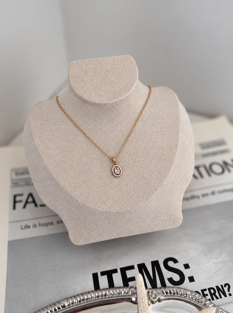 Halo Luxe Halskette in Gold mit ovalem Zirkonia-Anhänger auf heller Schmuckbüste
