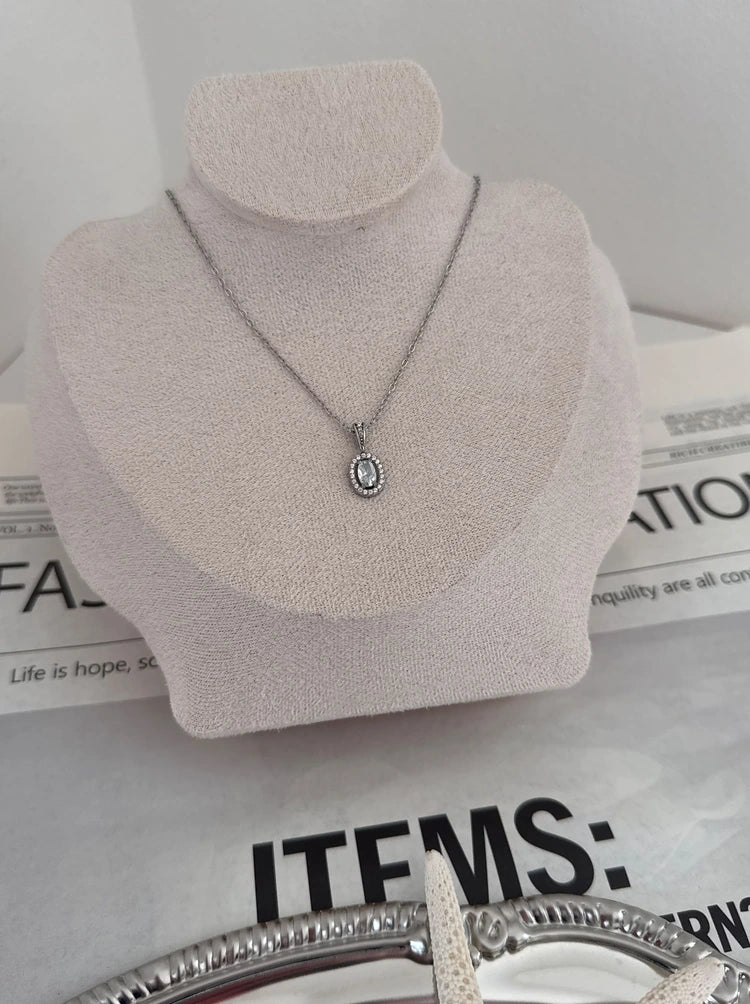 Halo Luxe Halskette in Silber mit ovalem Zirkonia-Anhänger auf heller Schmuckbüste