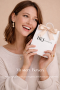 Glückliche Frau hält HEJSCHMUCK Mystery Box Geschenkverpackung mit wasserfestem Goldschmuck