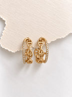 Leona Luxe Ohrringe in Gold auf weißem Seidenstoff mit Zirkonia-Pavé und Ankergliedern.