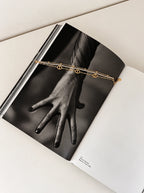 Mehrreihiges Livia Edelstahlarmband in Gold dekoriert auf einem Schwarz-Weiß-Fotobuch.