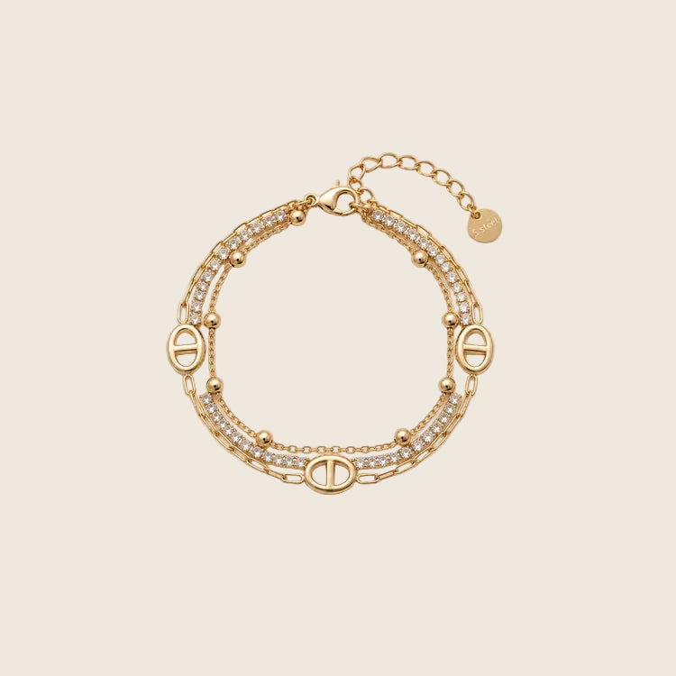 Livia Armband mehrreihig aus 14k vergoldetem Edelstahl mit Zirkonia-Kristallen und Karabinerverschluss auf hellem Hintergrund.