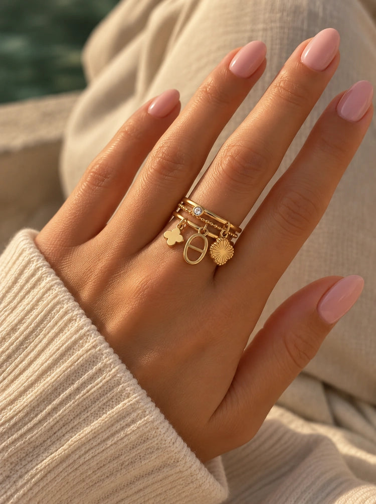 Hand trägt den Jolie verstellbaren Ring in Gold mit Blüte, Zirkonia und Perle am Strand