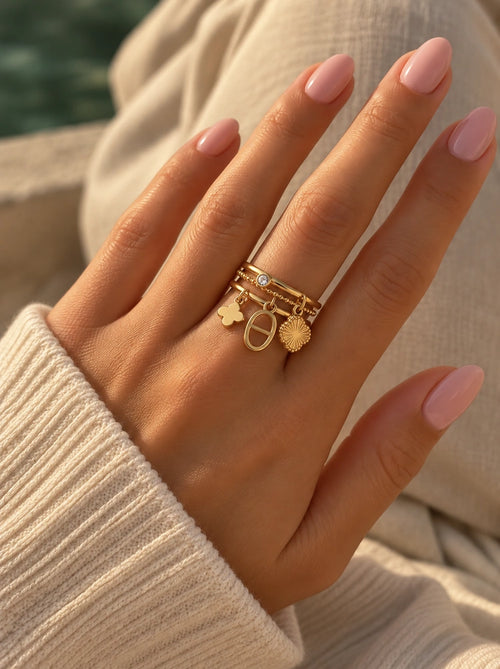Hand trägt den Jolie verstellbaren Ring in Gold mit Blüte, Zirkonia und Perle am Strand