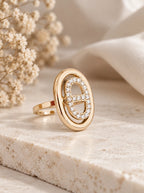 Lumina Ring in Gold mit ovalem Zirkonia-Glied auf heller Steinplatte