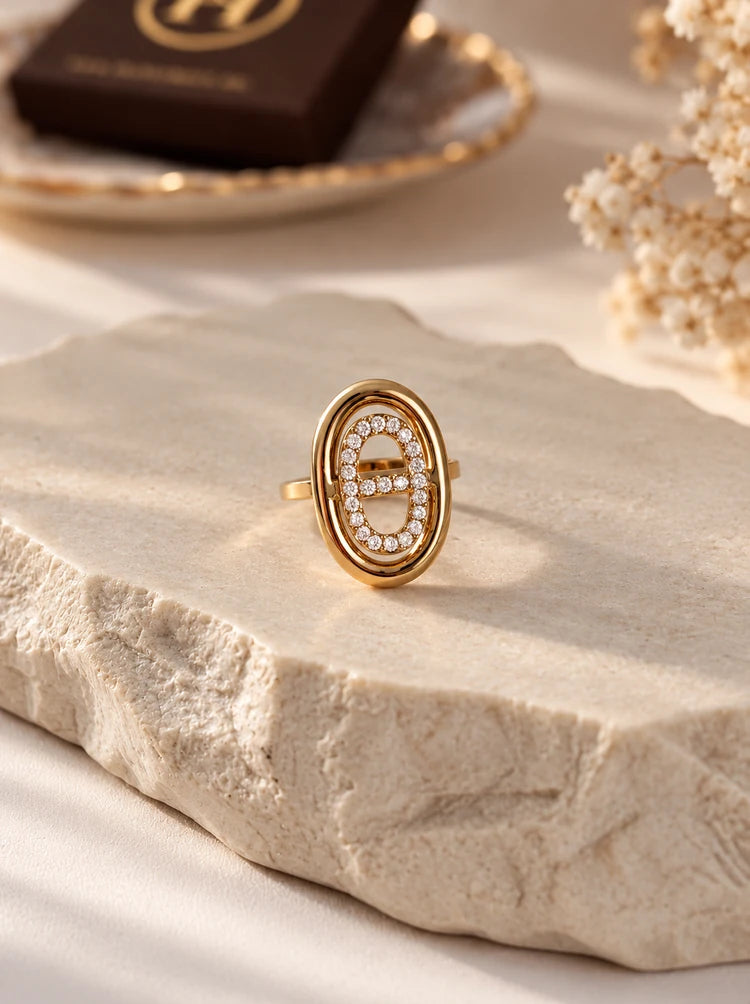 Lumina verstellbarer Ring in Gold mit Zirkonia auf heller Steinplatte neben Trockenblumen