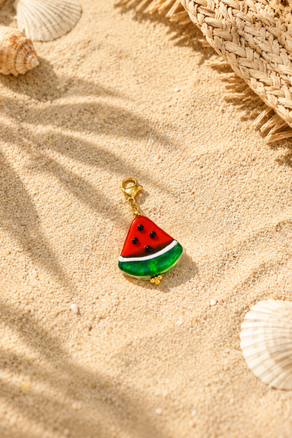 Melon Slice Charm Schmuckstück am Strand im Sand mit Muscheln – hejschmuck Sommer Style.