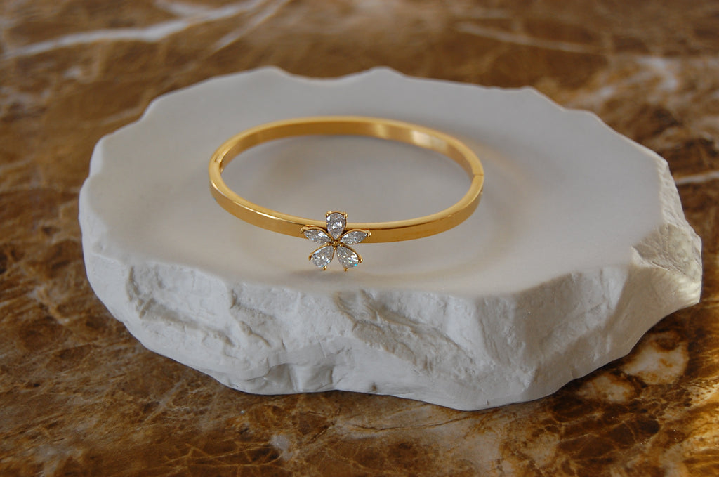 Eleganter goldfarbener Armreif aus Edelstahl mit 18K Vergoldung und funkelnden weißen Zirkonia in zarter Blumenform.