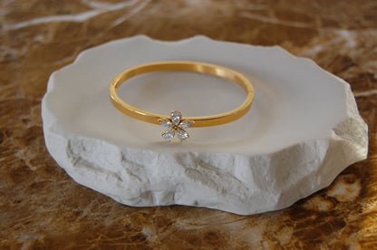 Eleganter goldfarbener Armreif aus Edelstahl mit 18K Vergoldung und funkelnden weißen Zirkonia in zarter Blumenform.