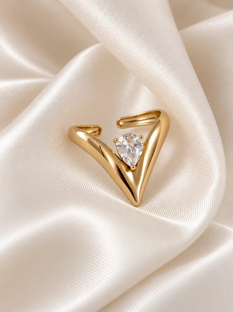 Verstellbarer Muse V-Ring aus 14k vergoldetem Edelstahl mit eingefasstem Zirkonia in Tropfenform auf weißer Seide.