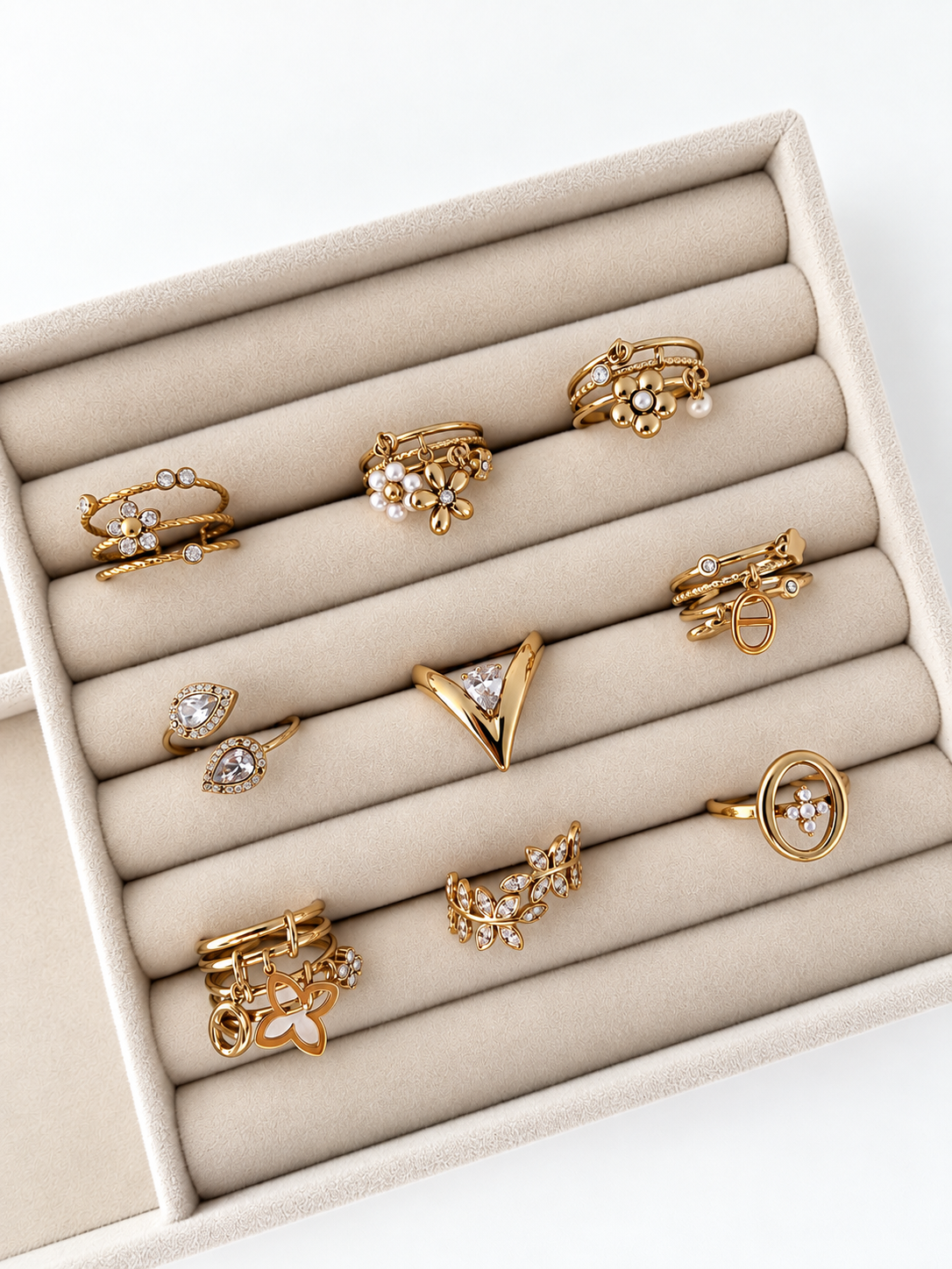 Muse V-Ring aus 14k vergoldetem Edelstahl präsentiert in einm beigen Samt-Schmucktablett neben weiteren Goldringen.