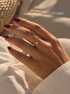 Hand am Strand trägt den Nala Ring in Gold mit Mini-Kleeblatt-Anhänger aus Zirkonia