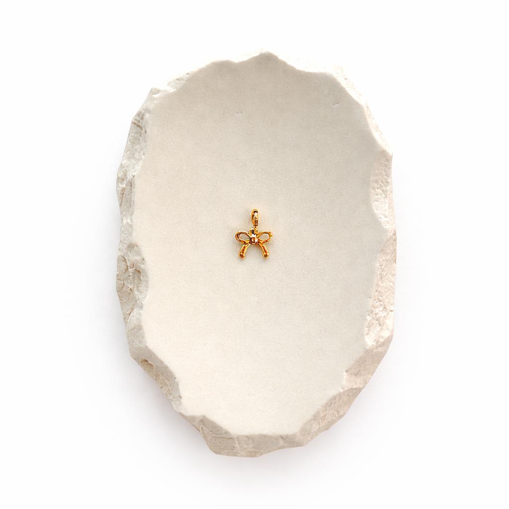 Kleine Schleifen-Anhänger Charm aus 14K vergoldetem Edelstahl auf hellem Stein