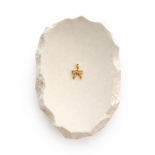 Kleine Schleifen-Anhänger Charm aus 14K vergoldetem Edelstahl auf hellem Stein