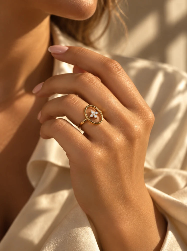 Hand trägt den Talia Ring in Gold mit Zirkonia-Blüte zur Seidenbluse